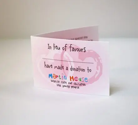 A folded card with a pink background reads, "In lieu of favours, we have made a donation to Martin House, hospice care for children and young people," perfect for incorporating thoughtful gestures into your wedding planning. The text is overlaid on a faint heart graphic.