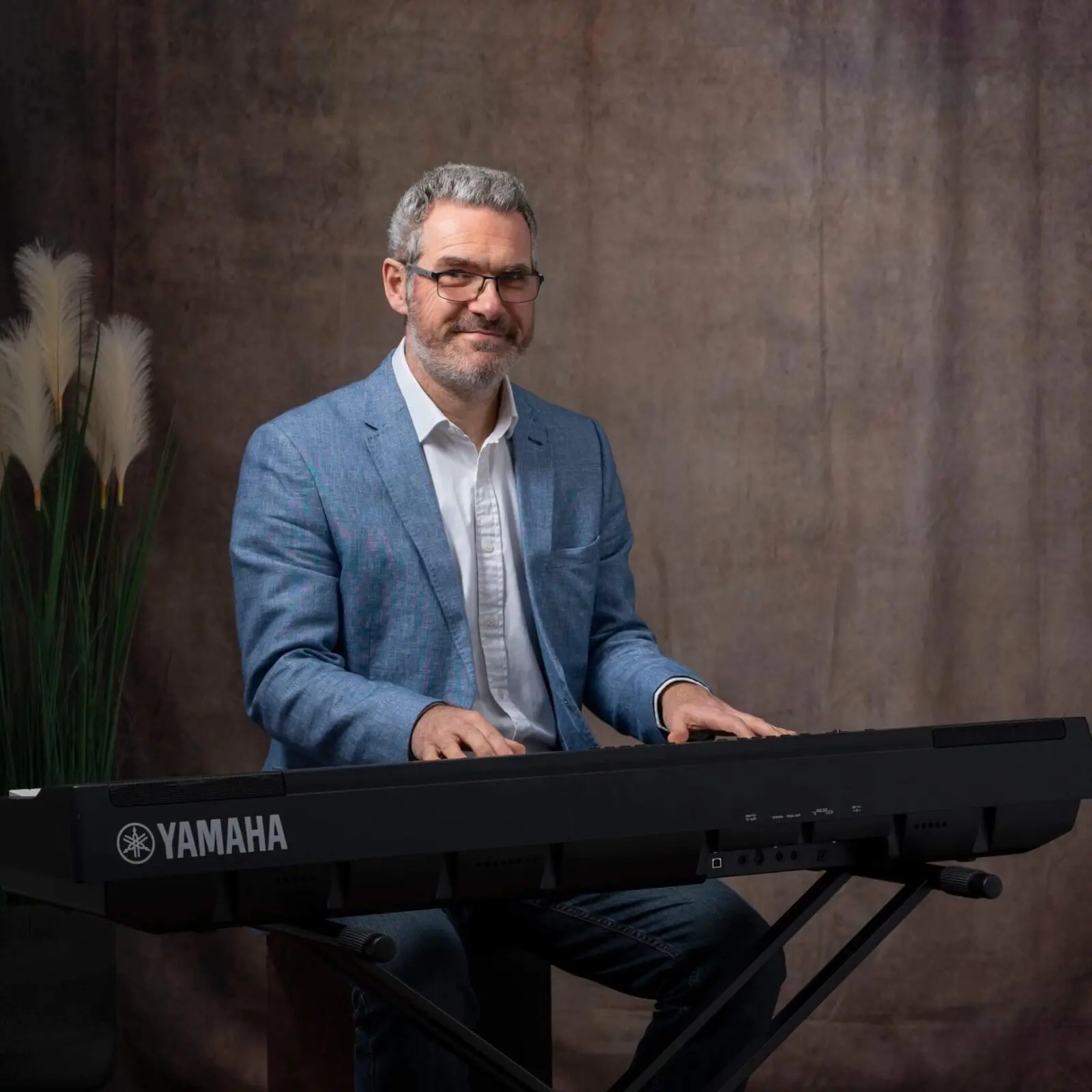 pianist in a blue jacket sits at a piano