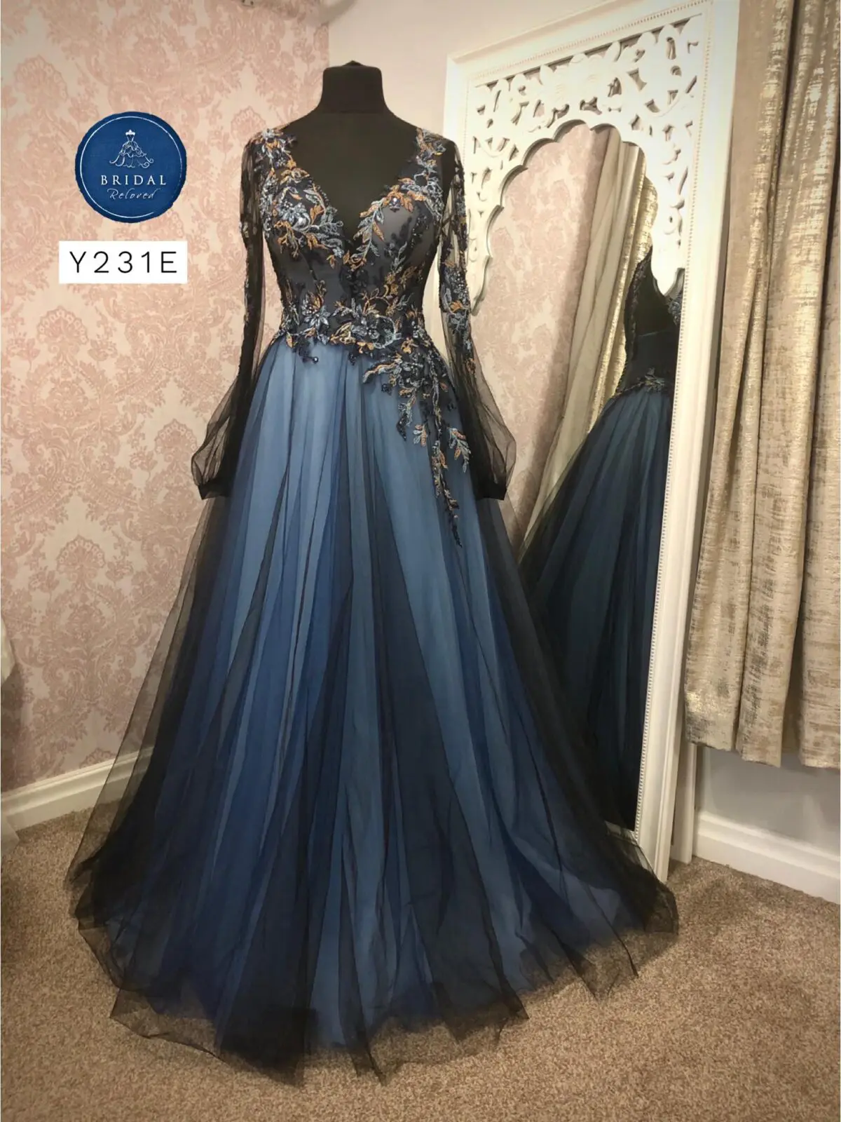An elegant blue and black gown with lace details is displayed on a mannequin in a beautifully decorated room, perfect for those deep into wedding planning.