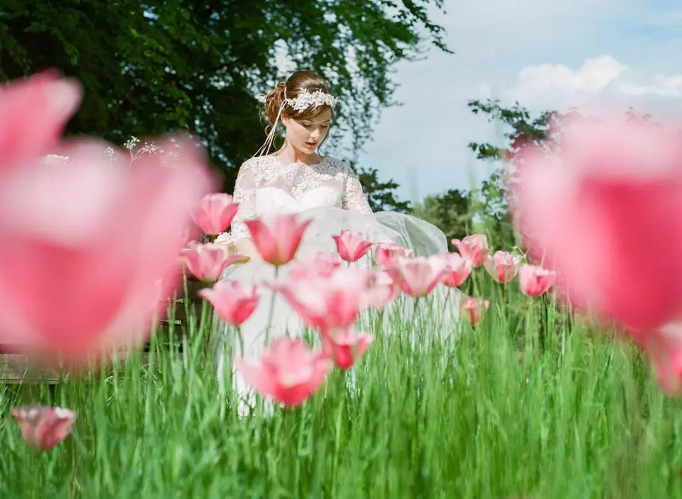 A bride is standing in a field of pink tulips during her wedding ceremony.