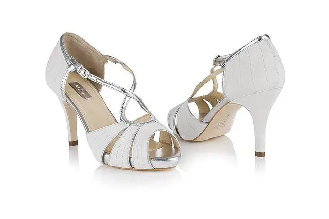 A pair of white high heeled wedding shoes on a white background.