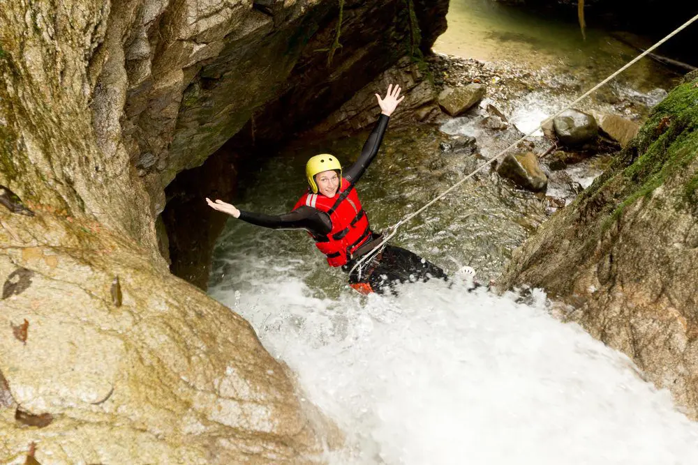 A man in a life jacket is navigating through the breathtaking canyon.