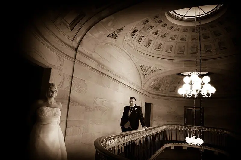 A bride and groom elegantly posing on a staircase for their wedding day.