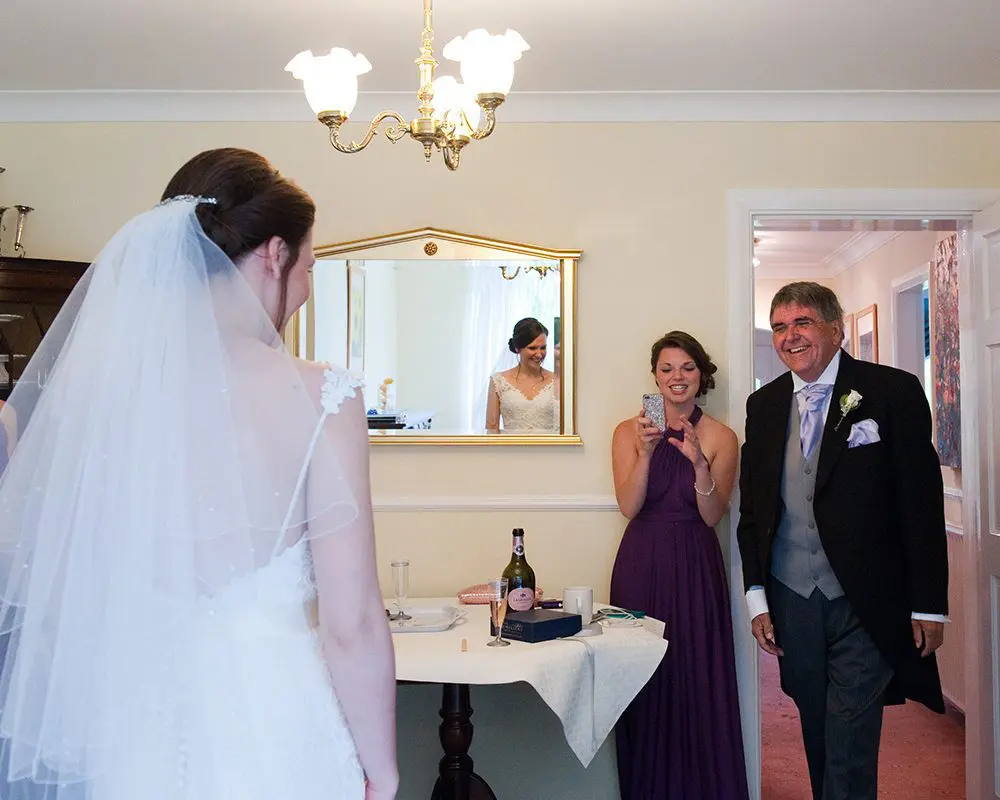 A bride and groom standing in front of a mirror, amidst their wedding planning process.