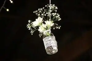 A mason jar filled with flowers hanging from the ceiling.