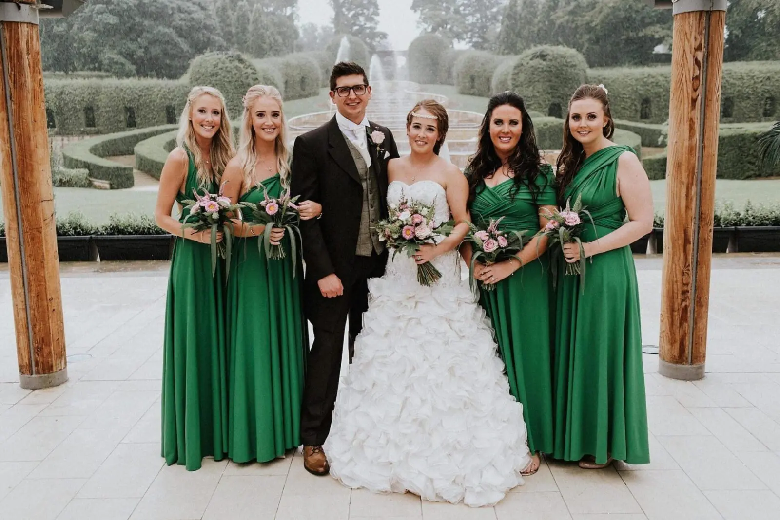 A group of bridesmaids in green dresses pose for a photo at a wedding.