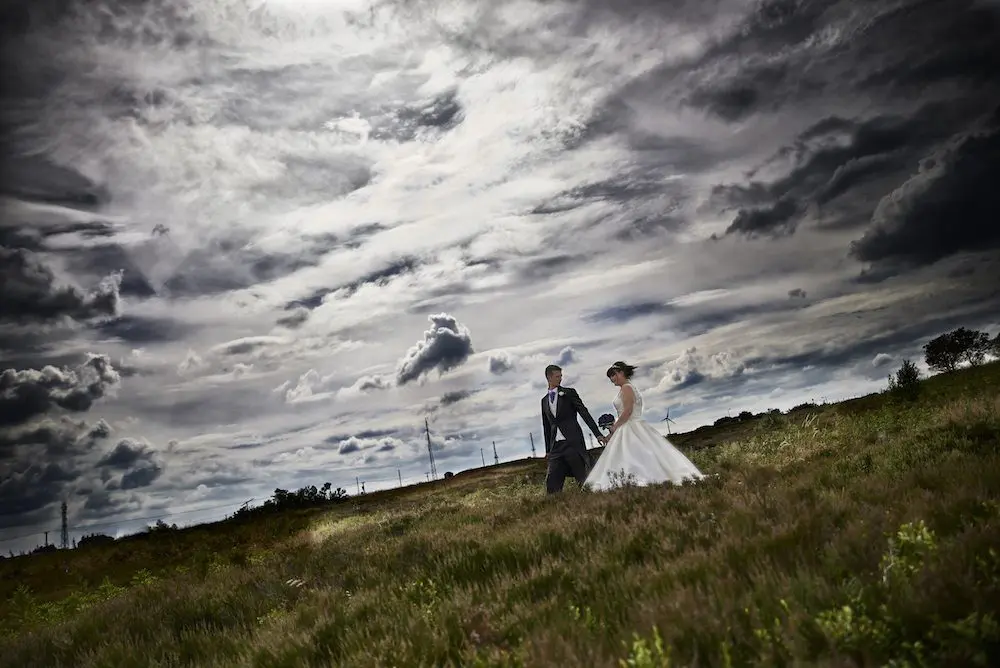 A bride and groom planning their wedding in a field under a cloudy sky.