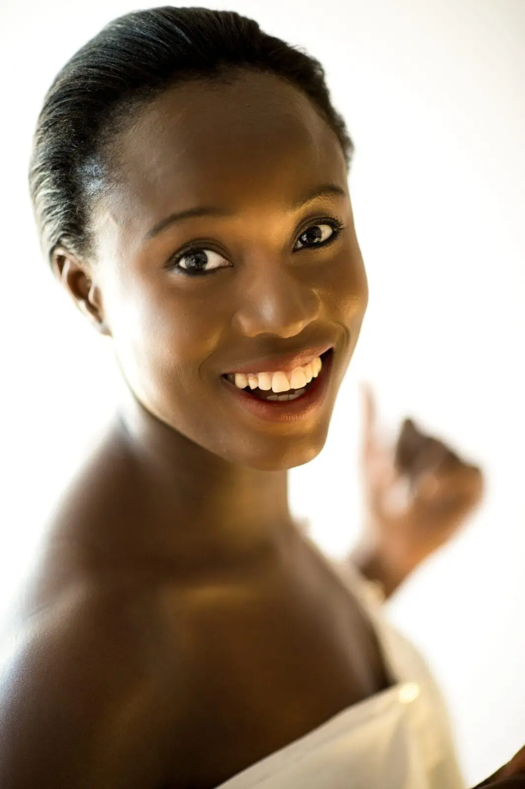 Lady in a white dress smiles showing perfect white teeth.