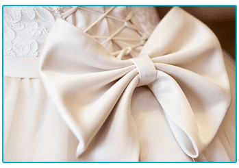 A close up of a wedding dress with a white bow, showcasing exquisite craftsmanship and elegance for your special day.