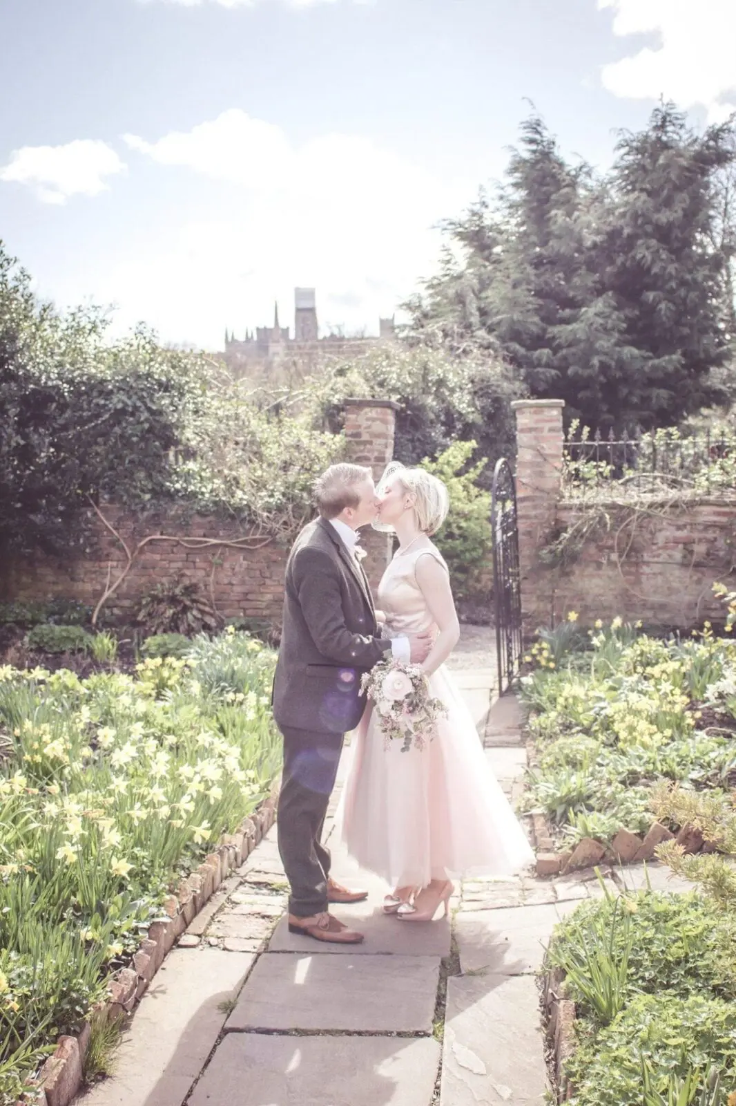 A bride and groom sharing a heartfelt kiss amidst the enchanting backdrop of a garden, creating a memorable wedding moment.