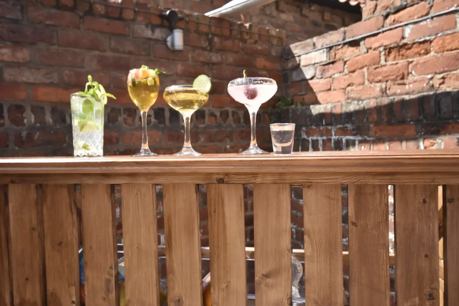 Wedding drinks on a rustic wooden railing against a charming brick wall.
