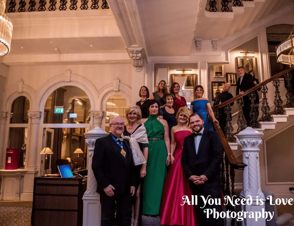A group of people posing in front of a wedding services.