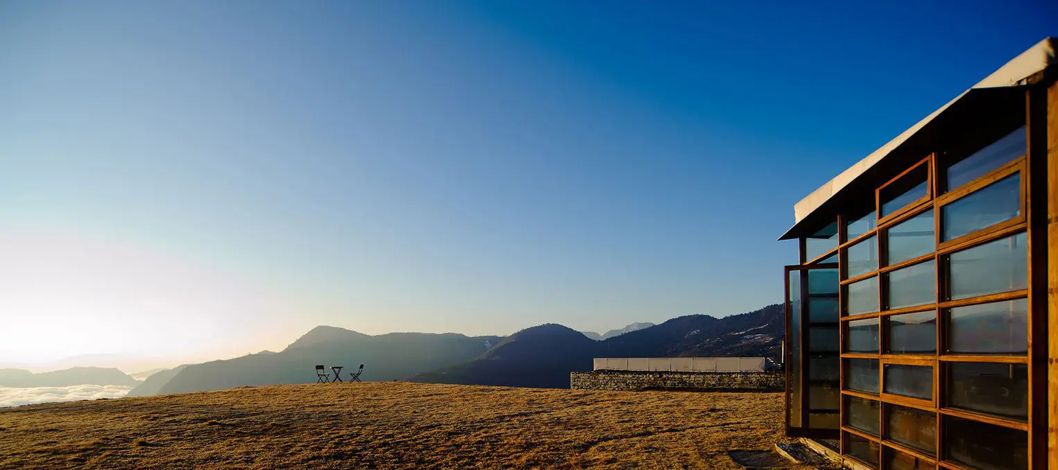 A picturesque wedding venue perched atop a scenic hill surrounded by majestic mountains.