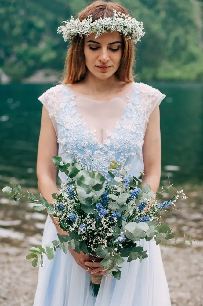 A bride in a blue dress holding a bouquet of blue flowers for her wedding.