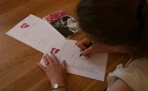 A woman writing on a piece of paper for her wedding services business in the UK.