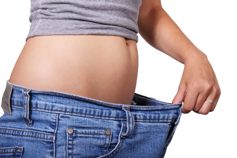 A woman is holding her stomach in her jeans while planning her wedding.