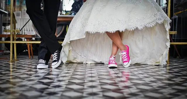 A bride and groom in pink converses standing on a tiled floor during their wedding ceremony.