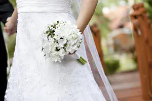 A bride and groom standing on a wooden walkway during their wedding.