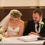 A bride and groom signing their wedding vows as part of their wedding planning process.
