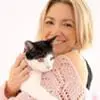 A woman holding a black and white cat while planning her wedding.