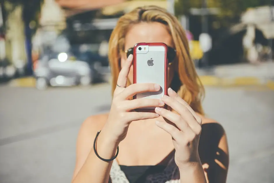 A woman is capturing a photo with her cell phone while involved in wedding planning.