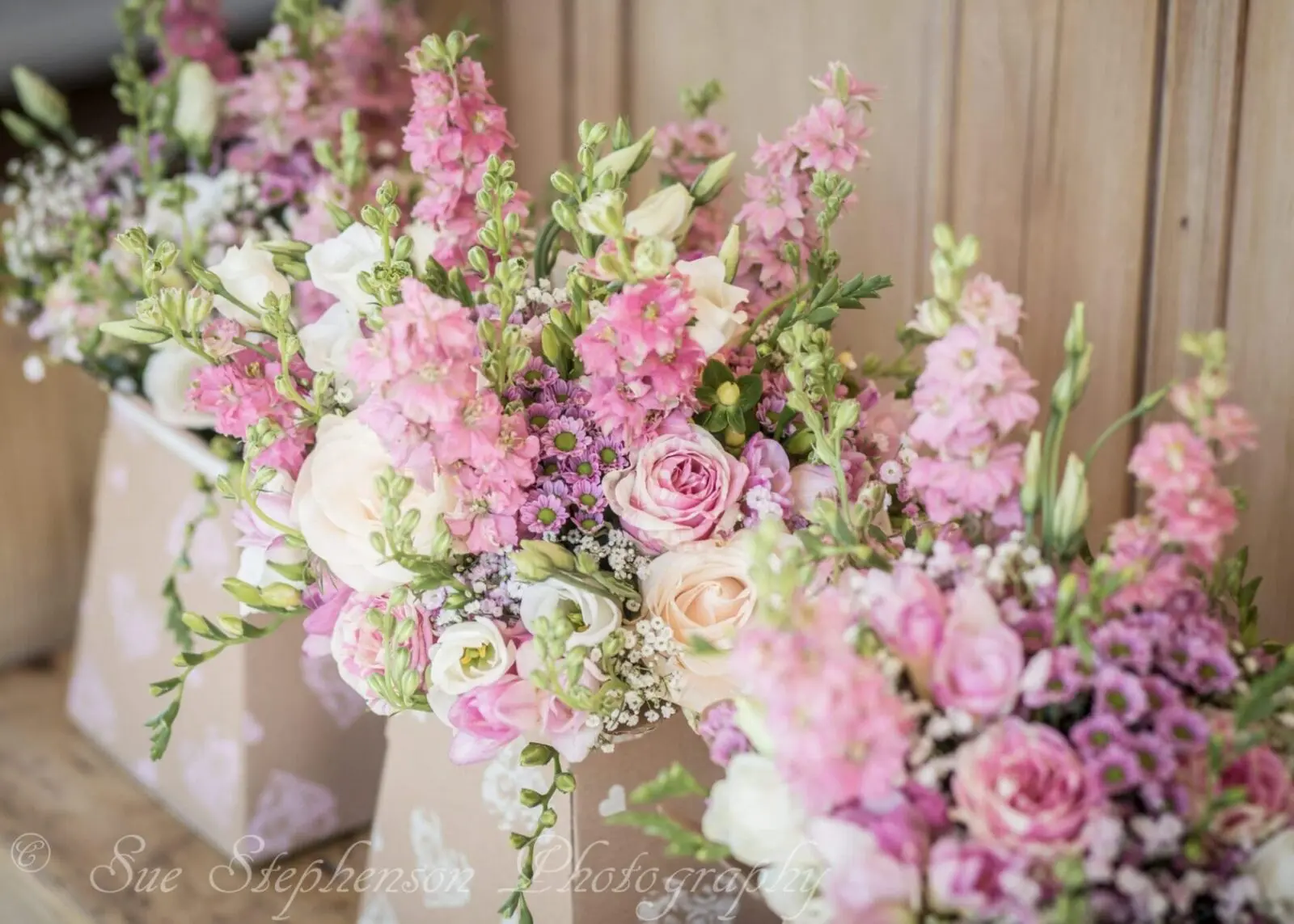 A bunch of pink flowers are sitting on a wooden table, perfect for wedding services or planning in the wedding business.