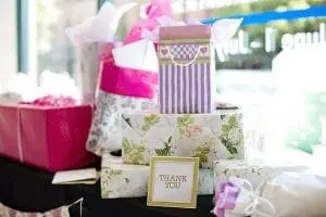 A table full of pink and purple wedding gift boxes.