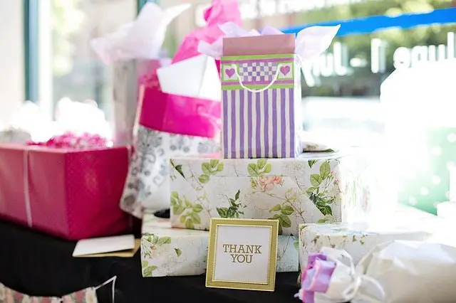 A table full of pink and purple wedding gift boxes.