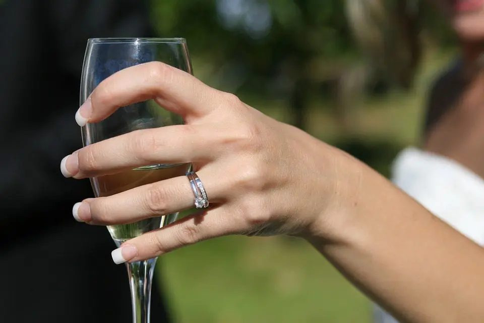 A bride's hand elegantly holding a glass of champagne at a wedding celebration.