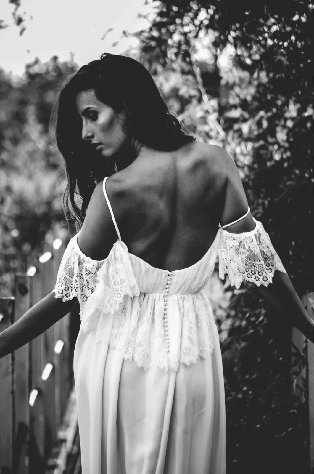 A woman in a white dress is standing on a bridge, perhaps contemplating her wedding plans.