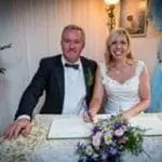 A bride and groom signing their wedding vows at a table in a wedding planning business in the UK.