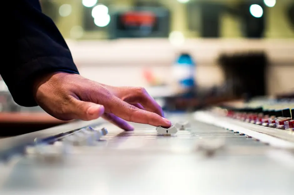 A person's hand on a mixing board in a recording studio, creating the perfect wedding soundtrack.