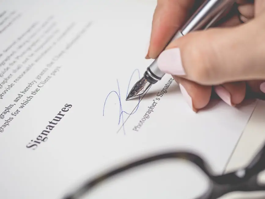 A person signing a wedding document with a pen.