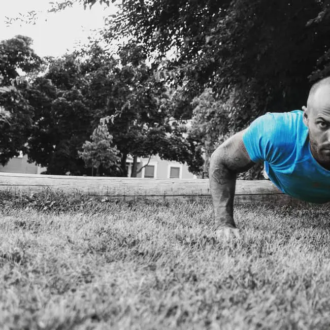 A man doing push ups in the grass during wedding planning.