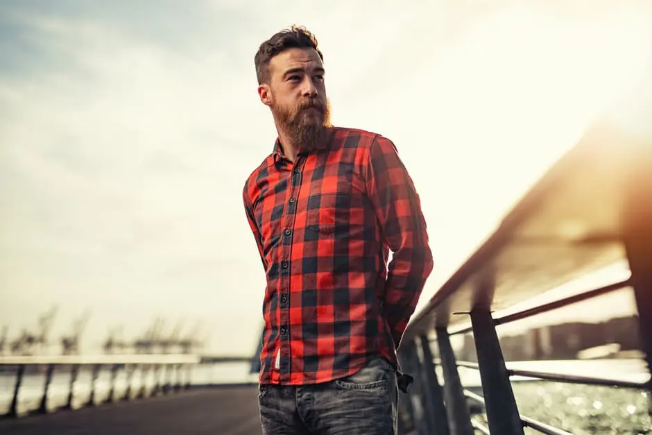 A bearded man wearing a red and black plaid shirt, available for wedding planning services.