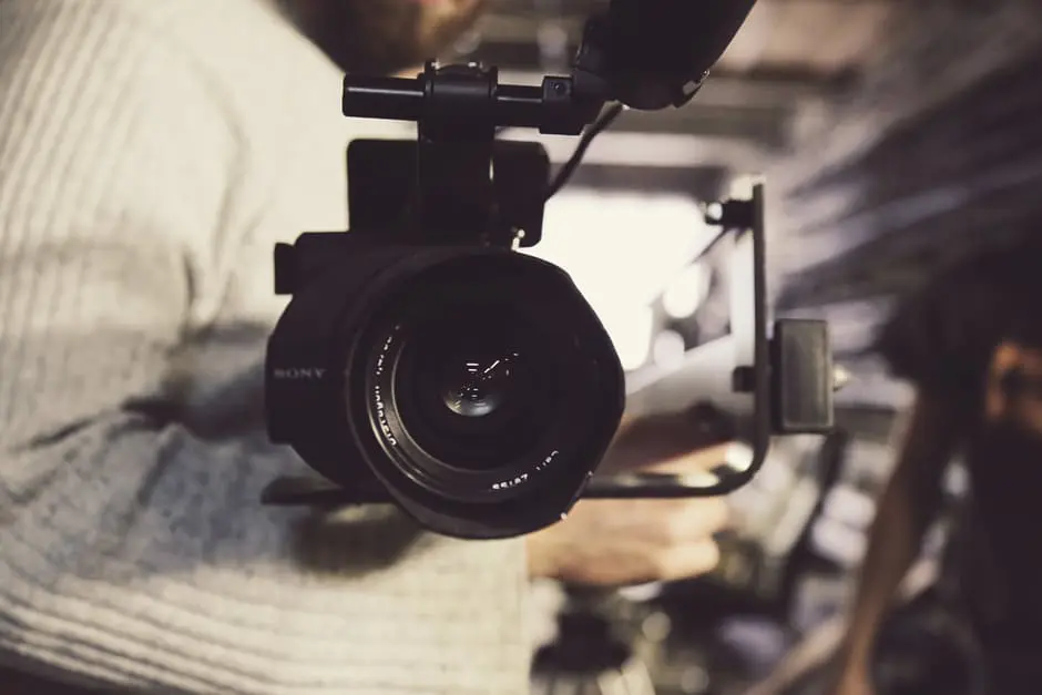 A man holding a video camera in a wedding planning warehouse.
