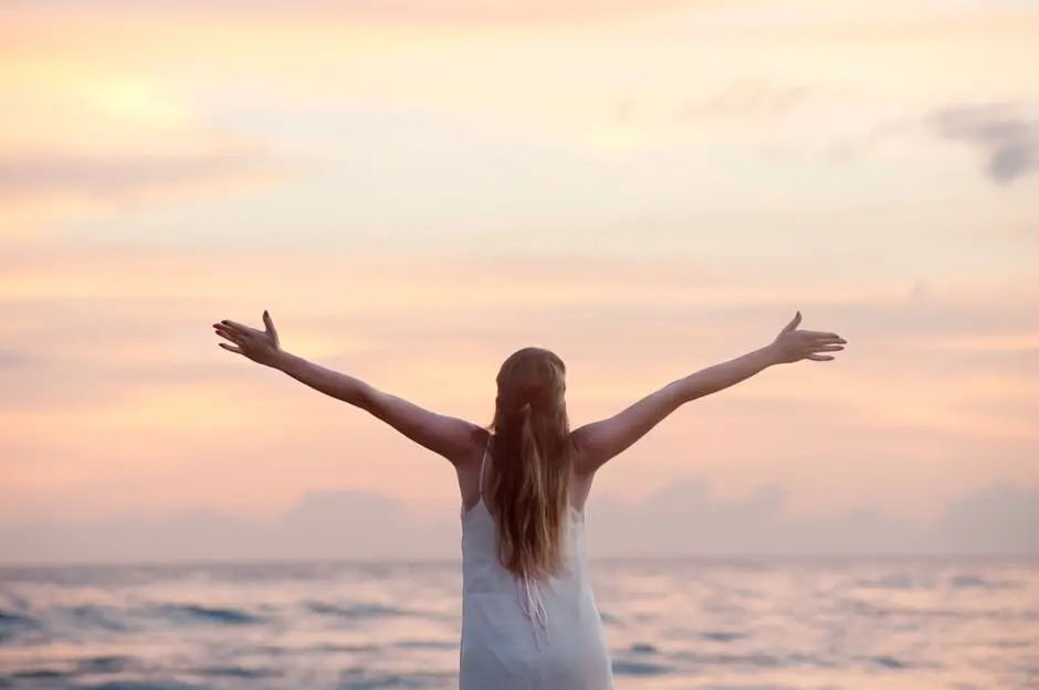 A woman standing on the beach with her arms outstretched, capturing a serene and breathtaking wedding moment in the UK.