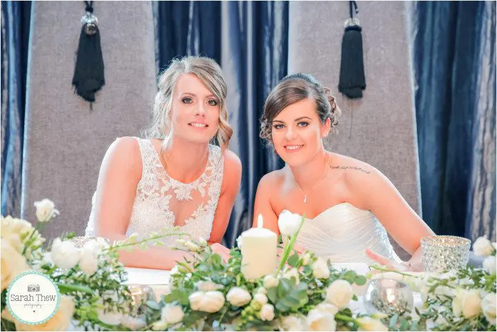 Two brides posing for a photo at their wedding reception, showcasing their beautiful wedding celebration.