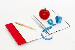 A wedding planning notebook with a red tomato and a measuring tape.