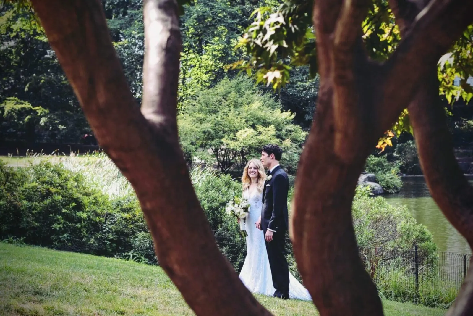 A bride and groom celebrating their wedding under the majestic trees of a park.