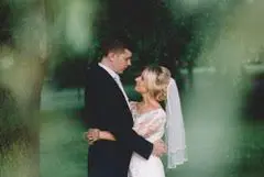 A bride and groom embracing under a wedding tree.