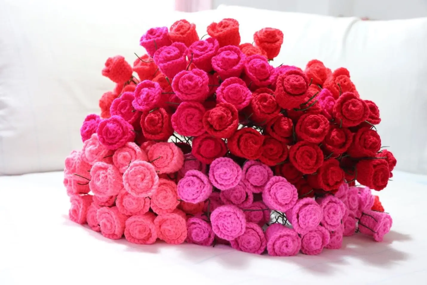 A bunch of pink and red roses on a bed.