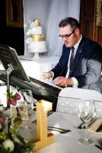 Musician plays piano during a wedding reception in front of guests.