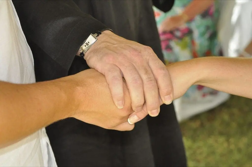 Three hands clasping each other, two adult hands on top of a child's hand, forming a supportive and comforting gesture—a beautiful symbol perfect for wedding planning as it captures the essence of unity and love in every cherished moment.