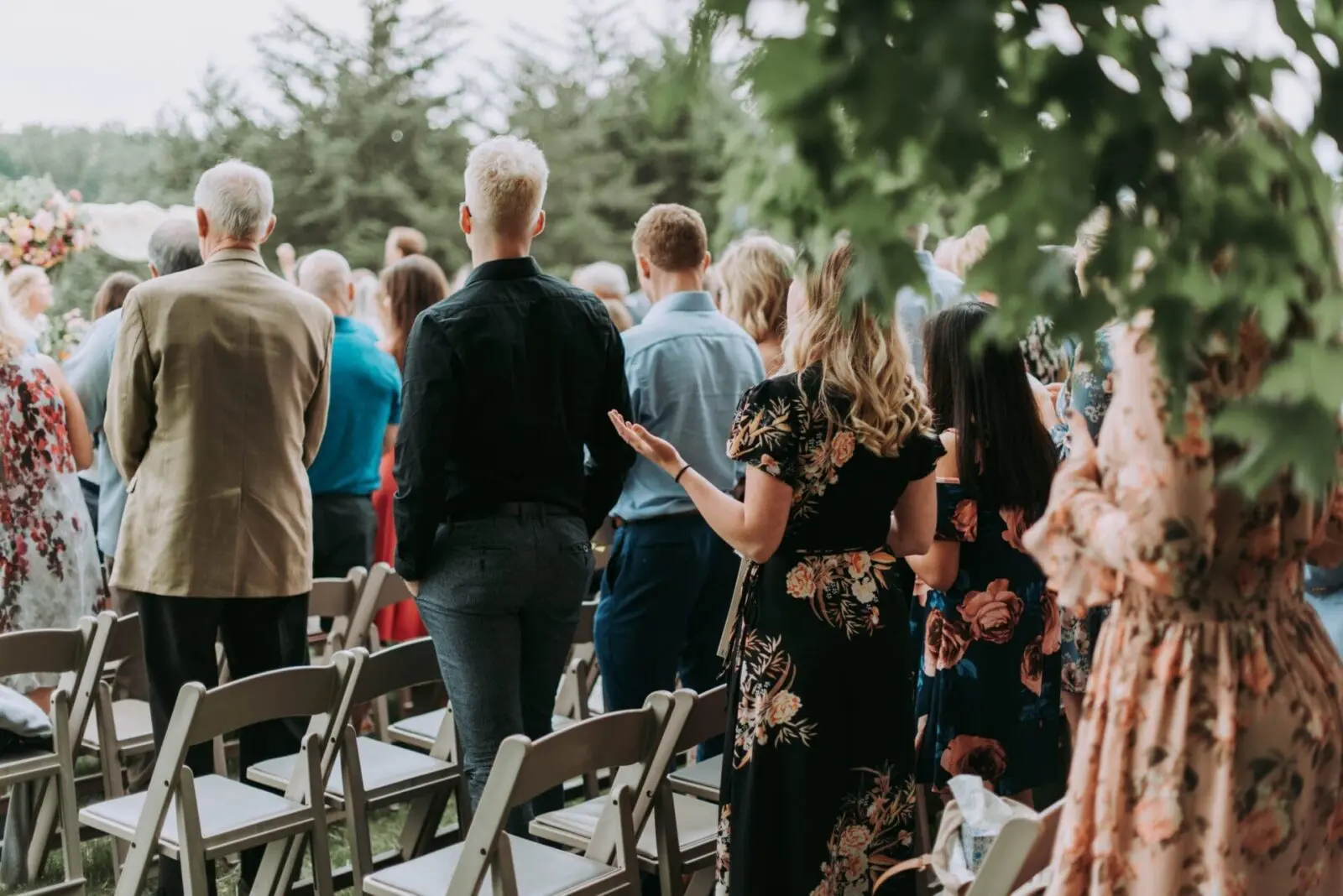 A group of people standing outdoors during a beautifully planned wedding ceremony, with trees visible in the background.