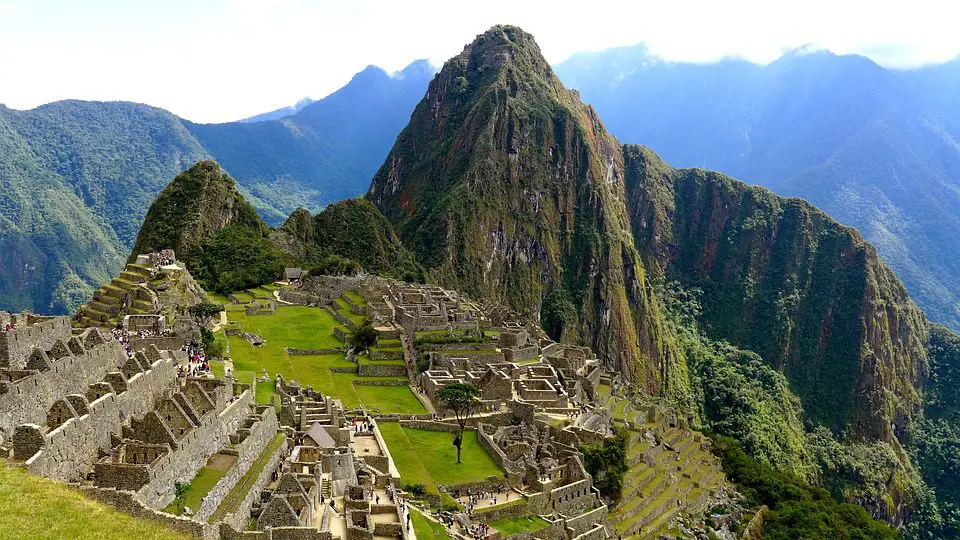 Panoramic view of Machu Picchu with ancient stone structures and terraces, perfect for inspiring wedding planning ideas, set against a backdrop of towering mountains under a clear sky.