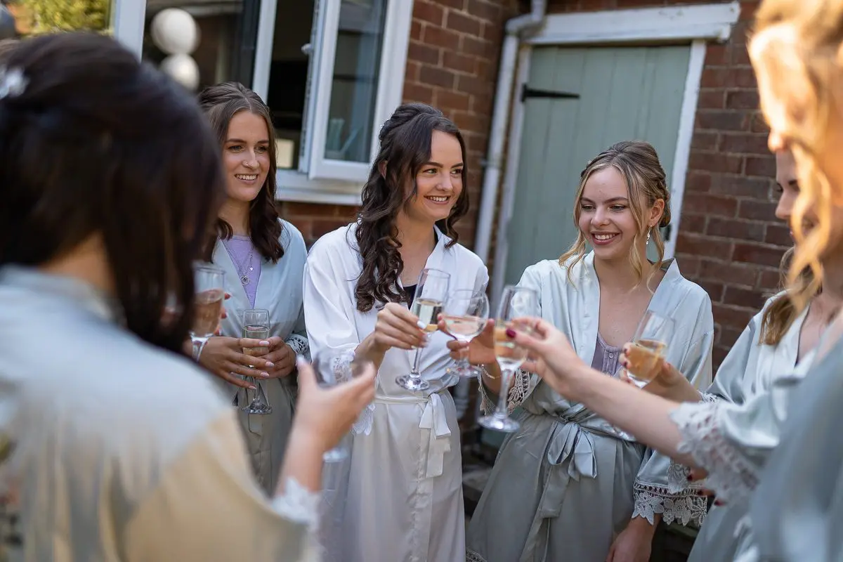 A group of people in robes are toasting with glasses of champagne outdoors, celebrating the joys of wedding planning.