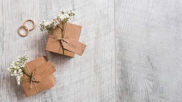 Two brown boxes with wedding rings and baby's breath on a wooden table.