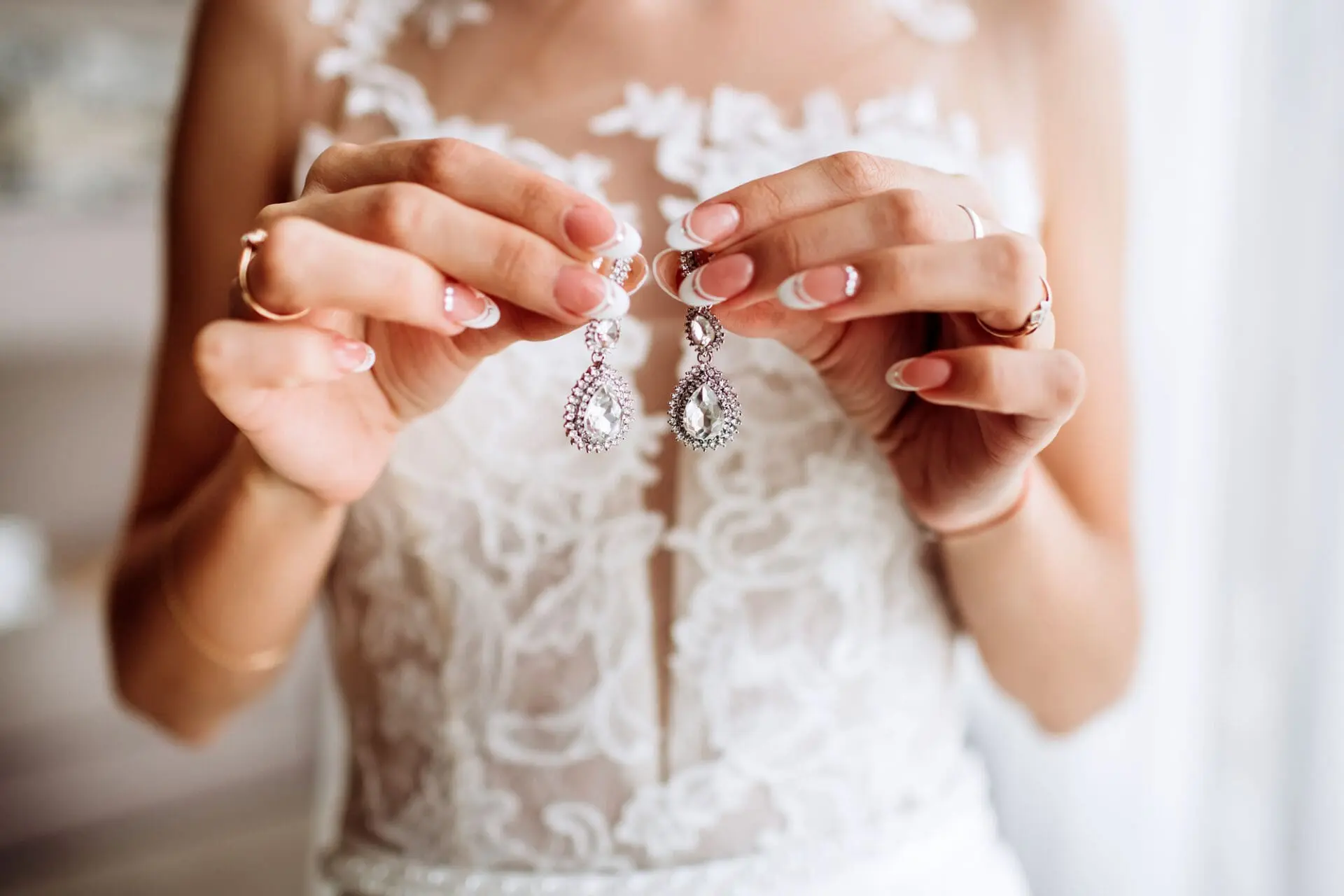 A bride holding a pair of earrings in her hands.