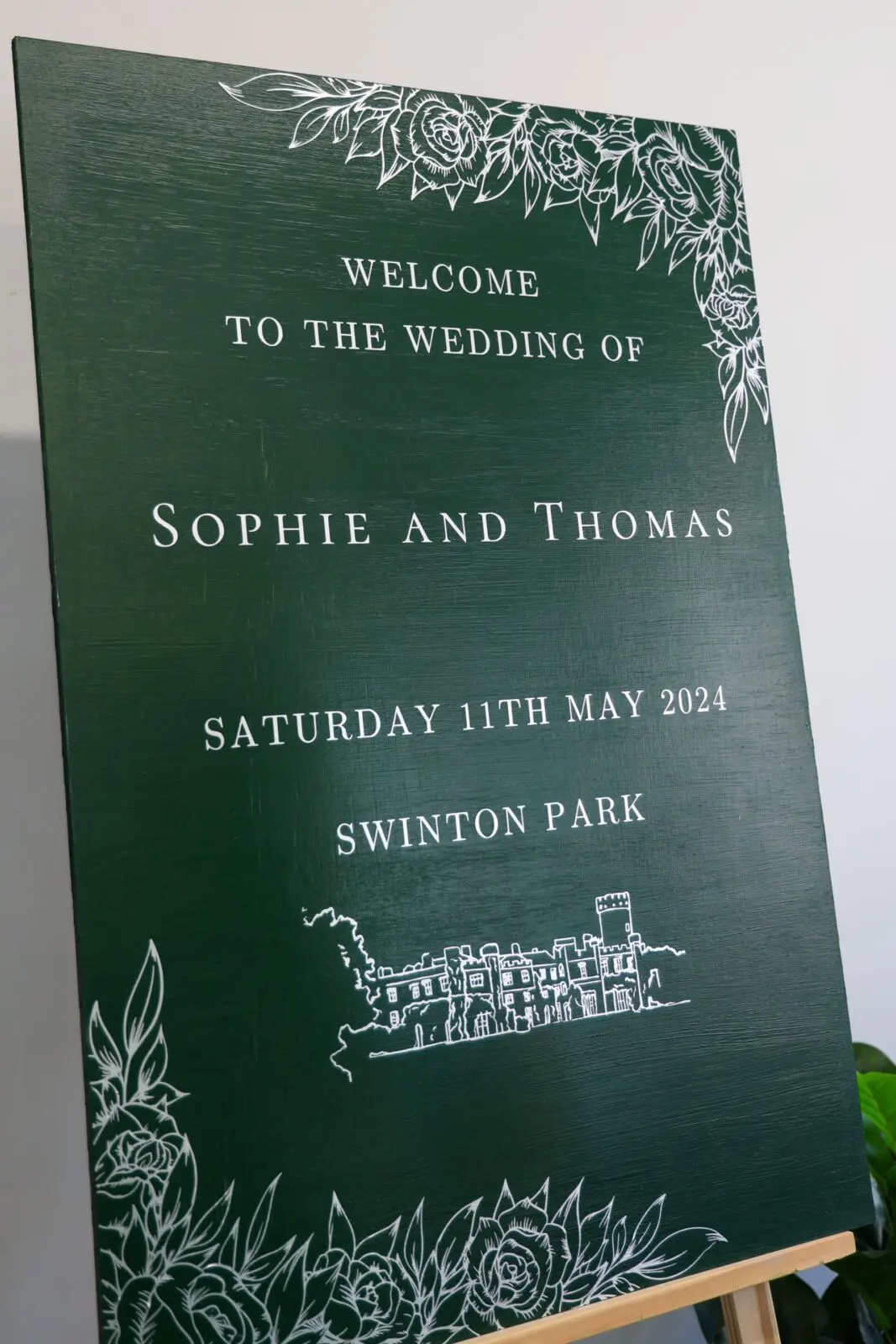 Emerald green welcome sign displayed at the entrance to a wedding venue.